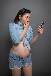 穿着时尚的孕妇拿着手机图片