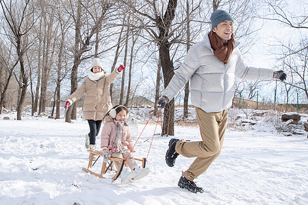 在雪地上玩雪橇的一家人图片