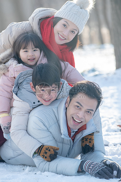 趴在雪地里玩耍的快乐家庭图片