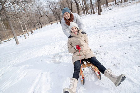 青年夫妇在雪地上玩雪橇图片