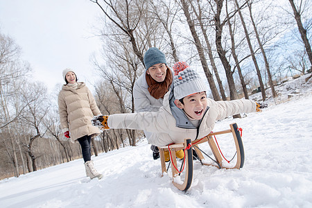 在雪地上玩雪橇的一家人图片