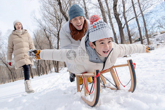 在雪地上玩雪橇的一家人图片