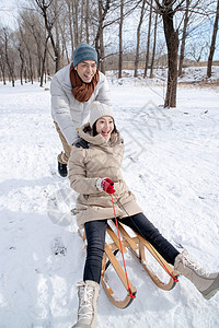 青年夫妇在雪地上玩雪橇图片