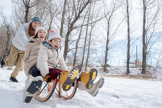 在雪地上玩雪橇的一家人图片