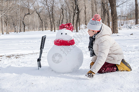 快乐的小男孩在雪地里堆雪人图片