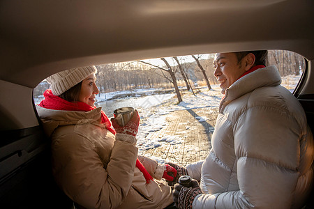 冬季热饮坐在汽车旁的青年夫妇背景