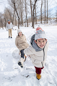 在雪地上玩雪橇的一家人高清图片