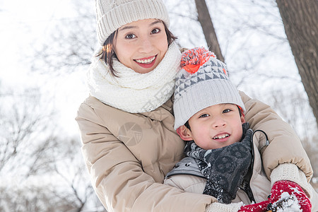 年轻妈妈带着孩子在雪地玩耍图片