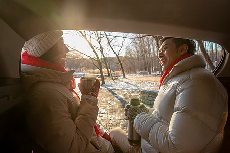 冬季热饮坐在汽车旁的青年夫妇背景
