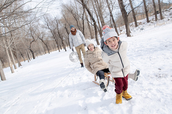 在雪地上玩雪橇的一家人图片