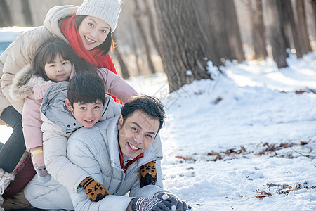 趴在雪地里玩耍的快乐家庭图片