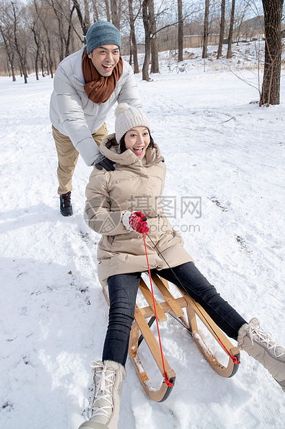 青年夫妇在雪地上玩雪橇图片