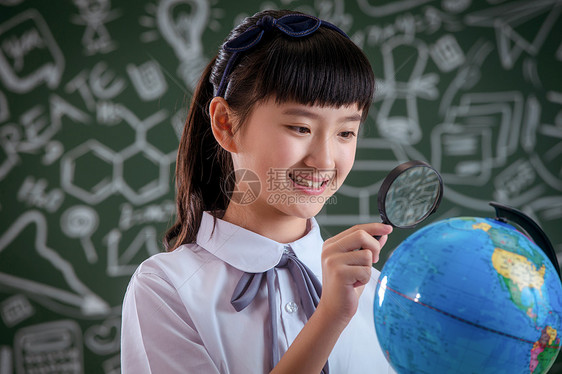 小学女生拿着放大镜看地球仪图片