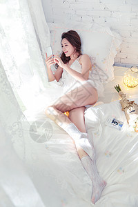 漂亮的青年女人躺在床上玩手机图片