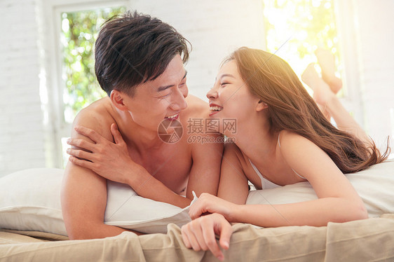 快乐的年轻情侣趴在床上图片
