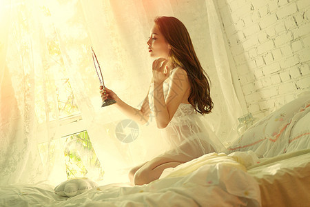 漂亮的青年女人坐在床上照镜子背景图片