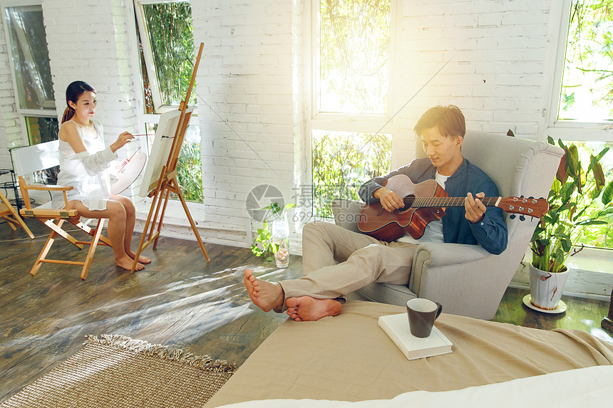 快乐的青年伴侣在家弹吉他画画图片