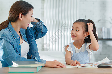 辅导女儿做作业的青年女人图片