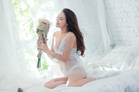 手拿花束的感年轻女人坐在床上图片