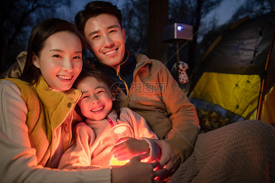 幸福的一家三口夜晚在野外露营图片