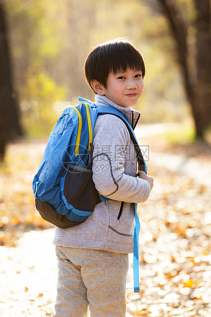 秋天户外小路上背书包的小男孩图片
