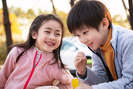 小孩坐蛋糕上可爱的男孩女孩户外野餐背景