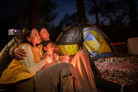 幸福的一家三口夜晚在野外露营图片
