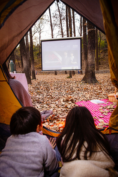 户外露营的儿童趴在帐篷里看电影图片