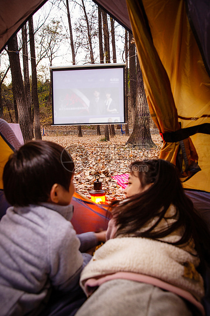 户外露营的儿童趴在帐篷里看电影图片