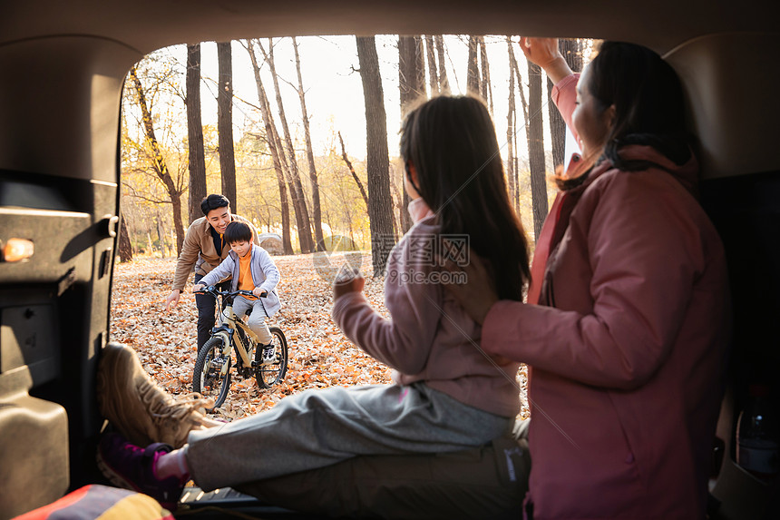 幸福母女在车中向学自行车的父子打招呼图片