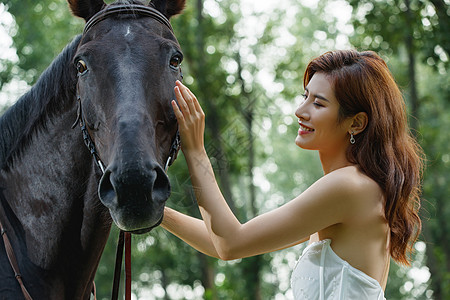 漂亮的青年女人抚摸骏马图片