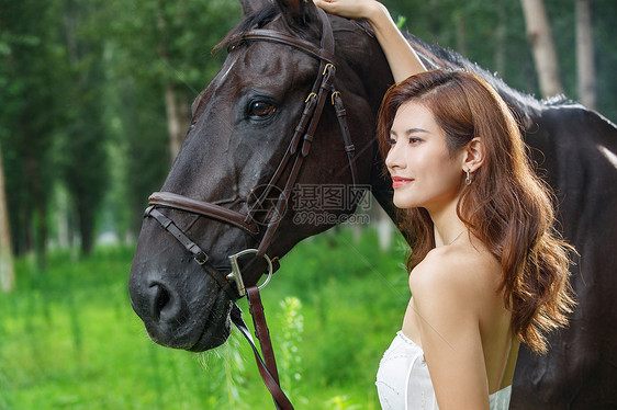 时尚的青年女人抚摸爱马图片