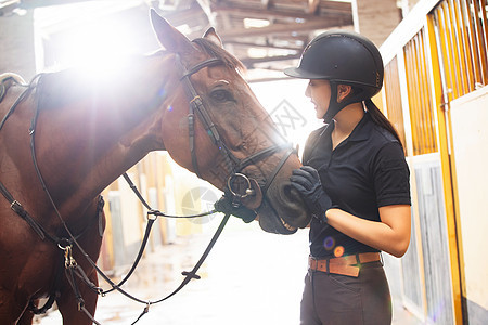 马厩里安抚马匹的年轻女子图片
