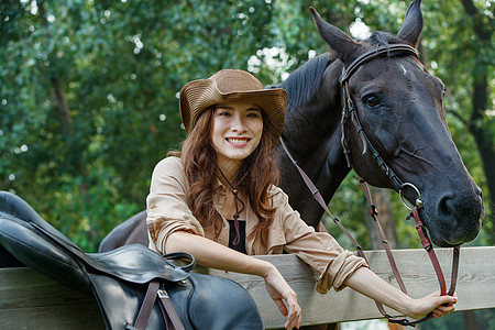 动物马趴在围栏上的快乐的青年女人牵着马背景