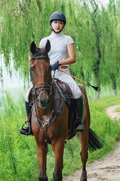 林间小路上骑马的帅气年轻女人图片
