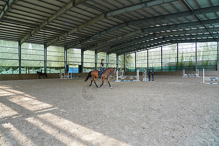 障碍训练场上骑马的青年女人图片