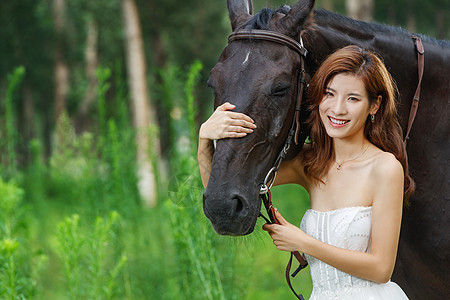 微笑美女草丛中漂亮的青年女人搂着马背景