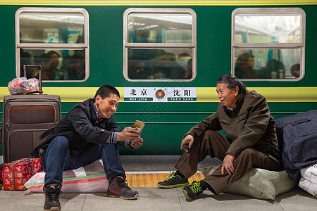 两名男子在火车月台上看手机图片