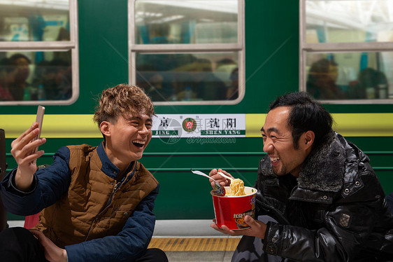 两名男子在火车月台上看手机图片