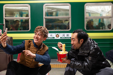 两名男子在火车月台上看手机背景图片