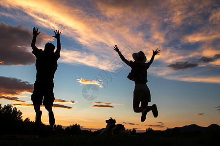 夕阳下的女性背影夕阳下跳跃的快乐夫妇背景