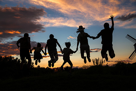 夕阳下手牵手跳跃的一家人图片