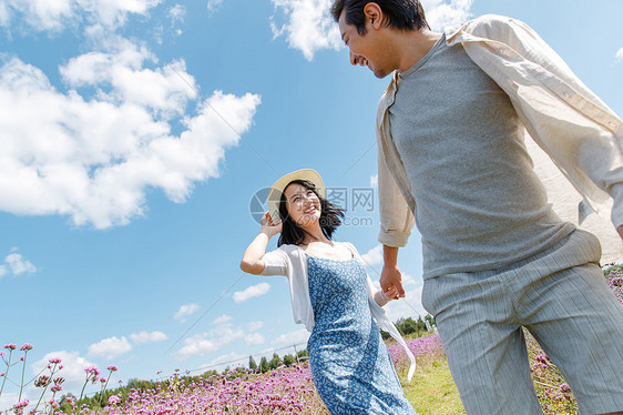 青年夫妇手牵手在花海里奔跑图片
