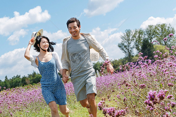 青年夫妇手牵手在花海里奔跑图片