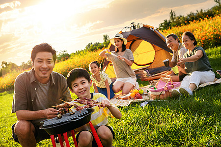 在烧烤孩子欢乐的一家人在郊外野餐烧烤背景