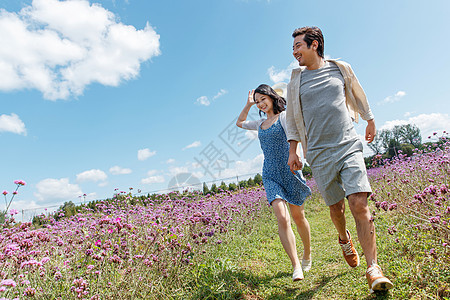 青年夫妇手牵手在花海里奔跑图片
