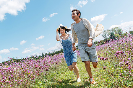 青年夫妇手牵手在花海里奔跑图片