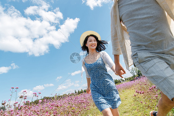 青年夫妇手牵手在花海里奔跑图片