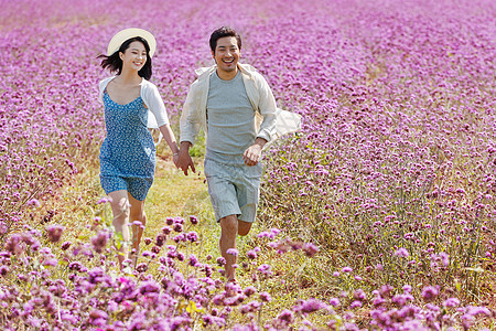 青年夫妇手牵手在花海里奔跑图片