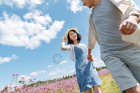 青年夫妇手牵手在花海里奔跑图片